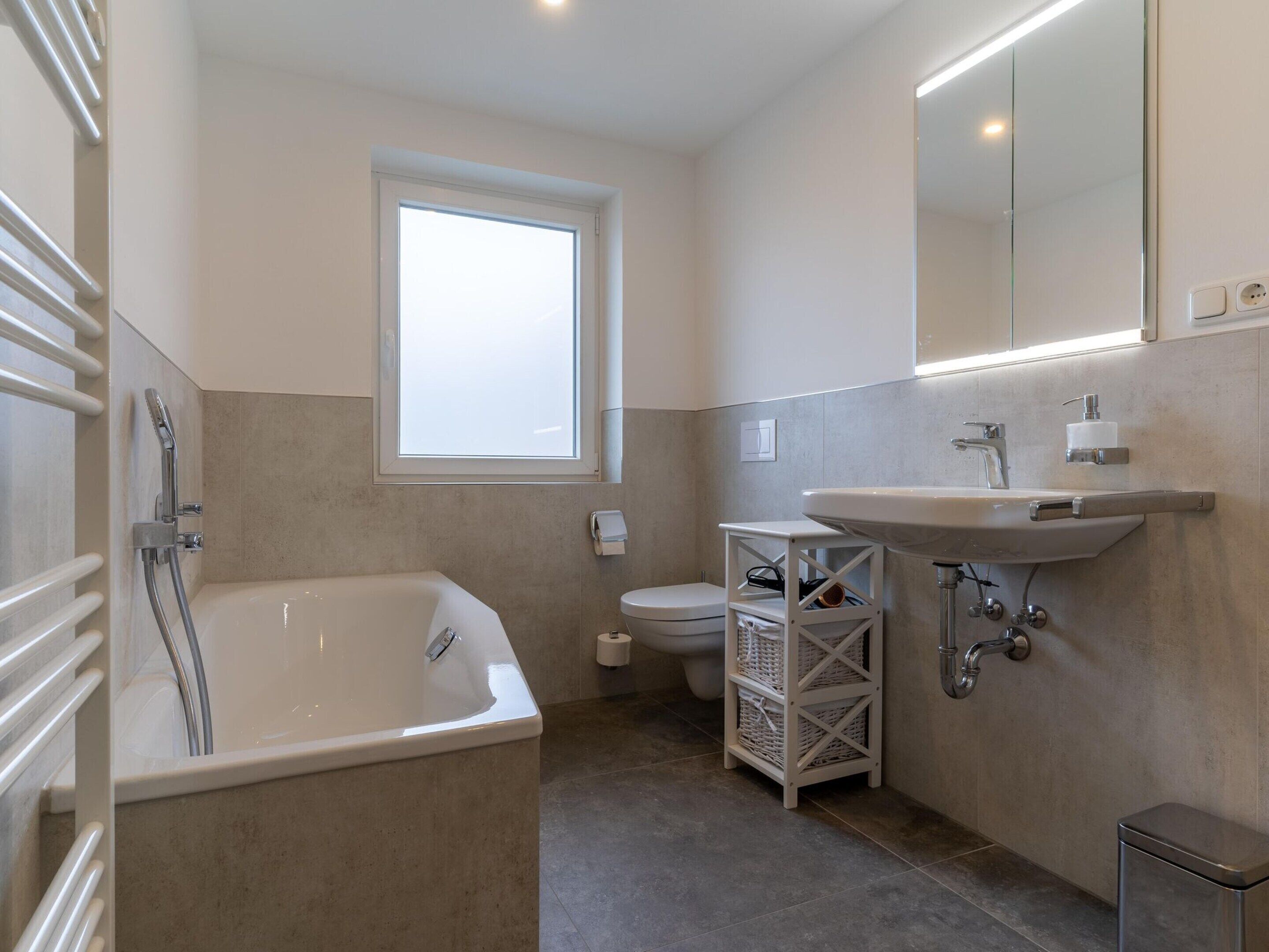 A modern bathroom with a bathtub, toilet, and sink.