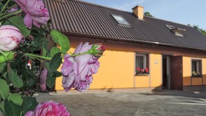 A building with a brown roof and yellow walls, featuring a door and windows. - Holiday Home in Stepniczka (Stepnica)