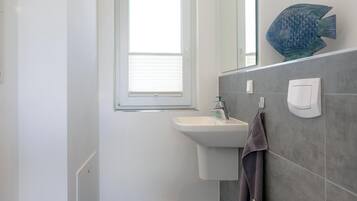 A bathroom with a window, a sink, and a towel rack.