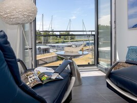 A modern room with a view of boats and docks through large windows.