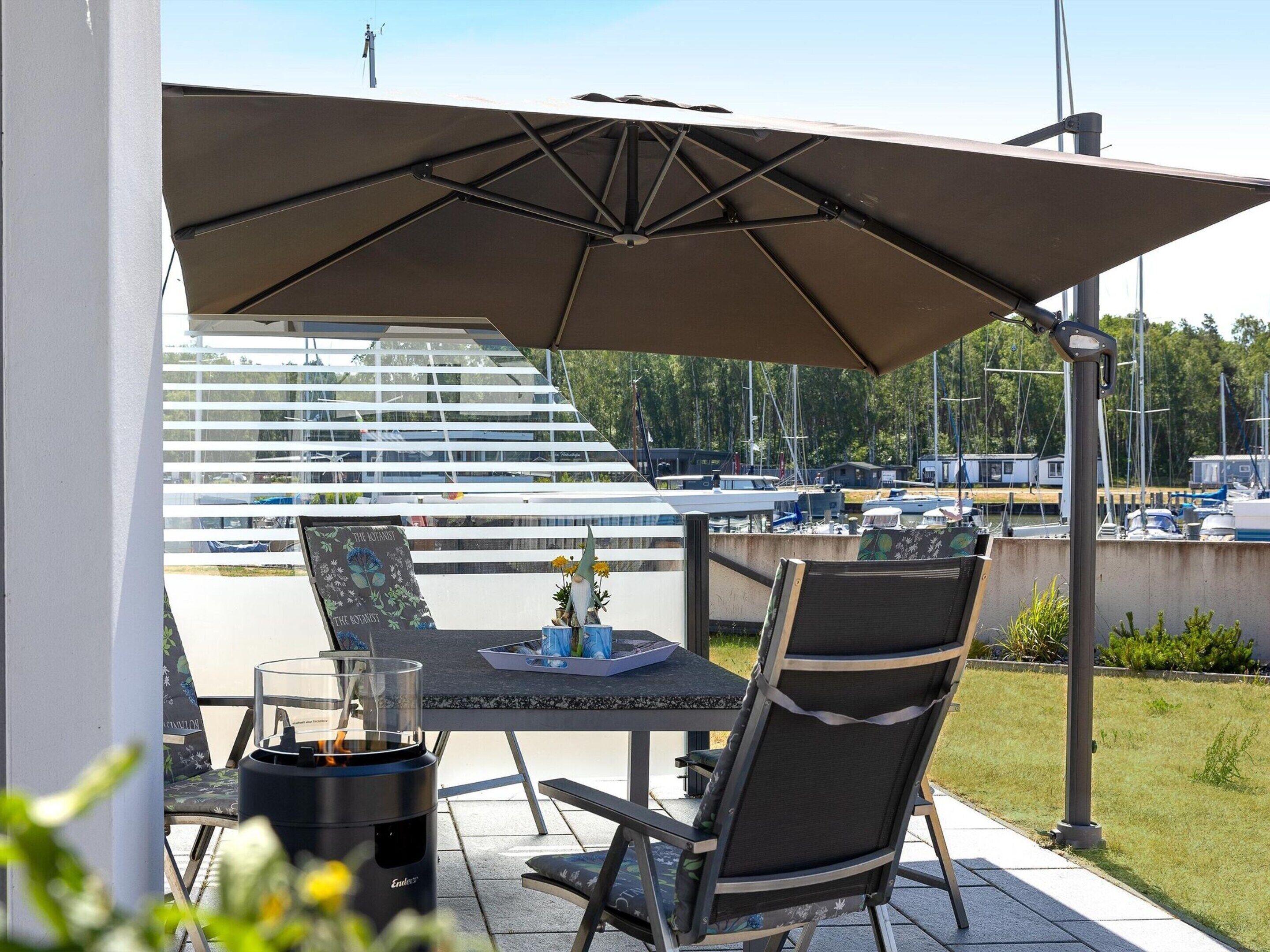 An outdoor patio with a table, chairs, and a large umbrella.