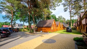 Uma pousada com cabanas de madeira, um caminho de paralelepípedos e árvores ao redor.