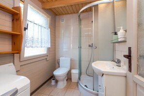 A compact bathroom with a toilet, shower, and sink.