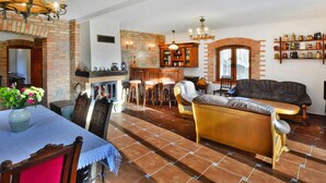 A spacious living room with a fireplace, a dining area with a table and chairs, a sofa, and a bar area with stools.