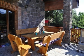 An outdoor patio with wooden furniture, stone walls, and a view of the surrounding area. - Comfortable Holiday Home in the Countryside (Szczecinek)