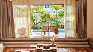A modern living room with a view of a pool and tropical plants. - Nila Residence (Canggu)