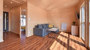 Un intérieur moderne avec des murs et des planchers en bois, un canapé gris, une table basse et un téléviseur fixé au mur.