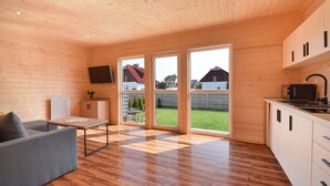 Un intérieur moderne avec des murs en bois, un canapé gris, une petite table et un coin cuisine.