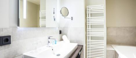 A modern bathroom with a white sink, mirror, and towel rack.