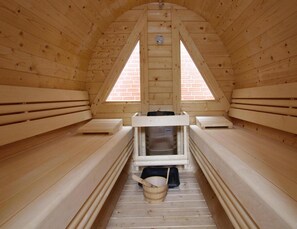 A wooden sauna with benches and a central heating unit. - Ferienwohnung in Westerland auf Sylt (Sylt)