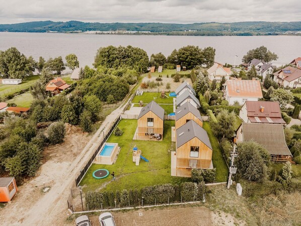 Vista aérea de un área residencial con casas, una piscina y una masa de agua extensa al fondo.