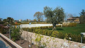 A landscaped area with a central paved space, surrounded by neatly trimmed hedges and a variety of trees. - Apartment in Lazise With Parking Space (Lazise)