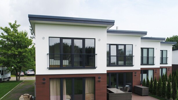 A modern two-story residential building with large windows, balconies, and a covered patio area. - Ferienhaus in Damp am Ostseestrand (Damp)