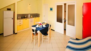 Una cucina compatta con un tavolo da pranzo per due persone, un frigorifero e un armadietto rosso.