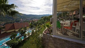 Un edificio moderno con facciata in vetro che si affaccia su una piscina e vegetazione lussureggiante.