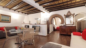 A spacious living area with a dining table, chairs, a sofa, and a TV. - Loft Apartment Termini Colosseum (Roma)