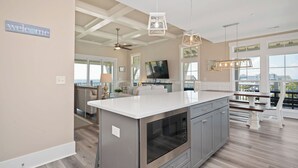 A modern kitchen with a large island, built-in appliances, and a view to the outside. - A New Hope: Ocean View with Private Pool and Easy Beach Access (Oak Island)