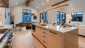 A modern kitchen with a large island, wooden cabinets, and pendant lighting. - 1060 Park Ski Magnificent Mountain Retreat 5 Bedroom Home by RedAwning (Park City)