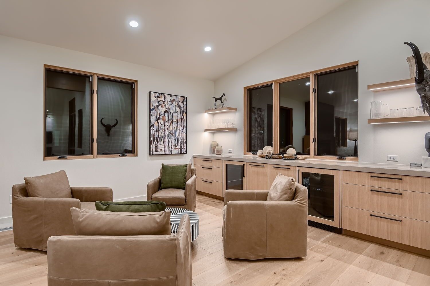 A modern living room with a kitchen area, featuring a sofa set, a dining table, and a kitchen counter.