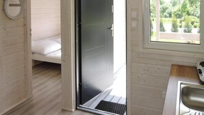 A modern room with a bed, a door leading to a balcony, and a kitchen area with a sink and stove. - Bungalow in Kolczewo Near Baltic Sea Beach (gmina Wolin)