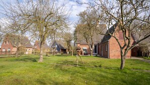 A residential area with houses, a swing set, and a clear sky. - Ferienhaus in Garding (Garding)