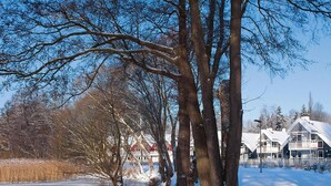 A snow-covered landscape with a row of houses along a frozen river. - Appartements im Schlosspark Bad Saarow (Bad Saarow)