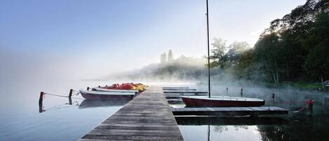 A wooden pier extending into calm water with boats docked at the end.
