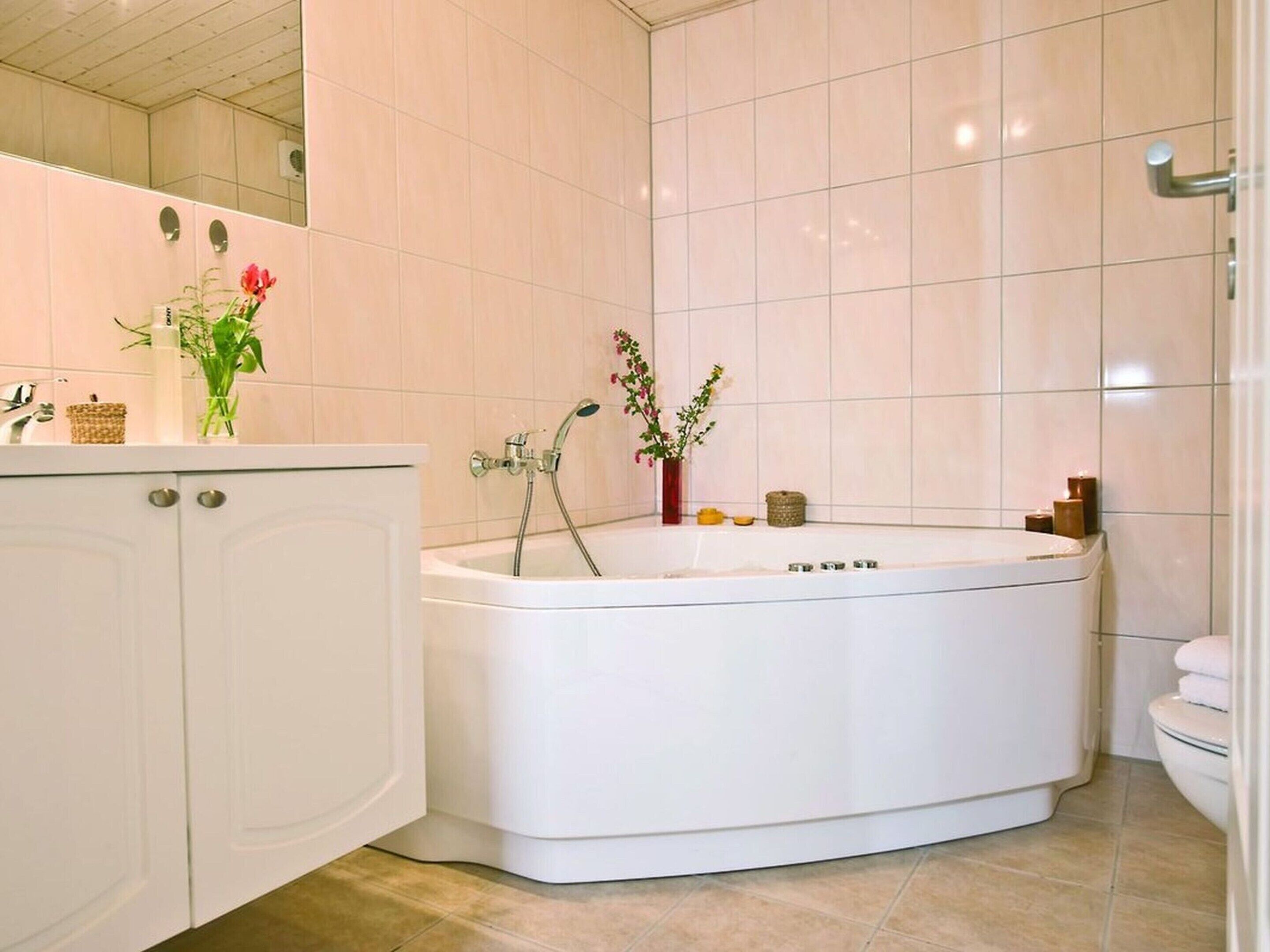 A modern bathroom with a freestanding bathtub, a white vanity with a mirror, and a toilet.