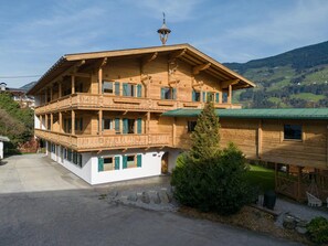 A multi-story wooden chalet with balconies, a green roof, and a mountainous backdrop. - Apartment in Fugen Near Spieljochbahn (Fuegen)