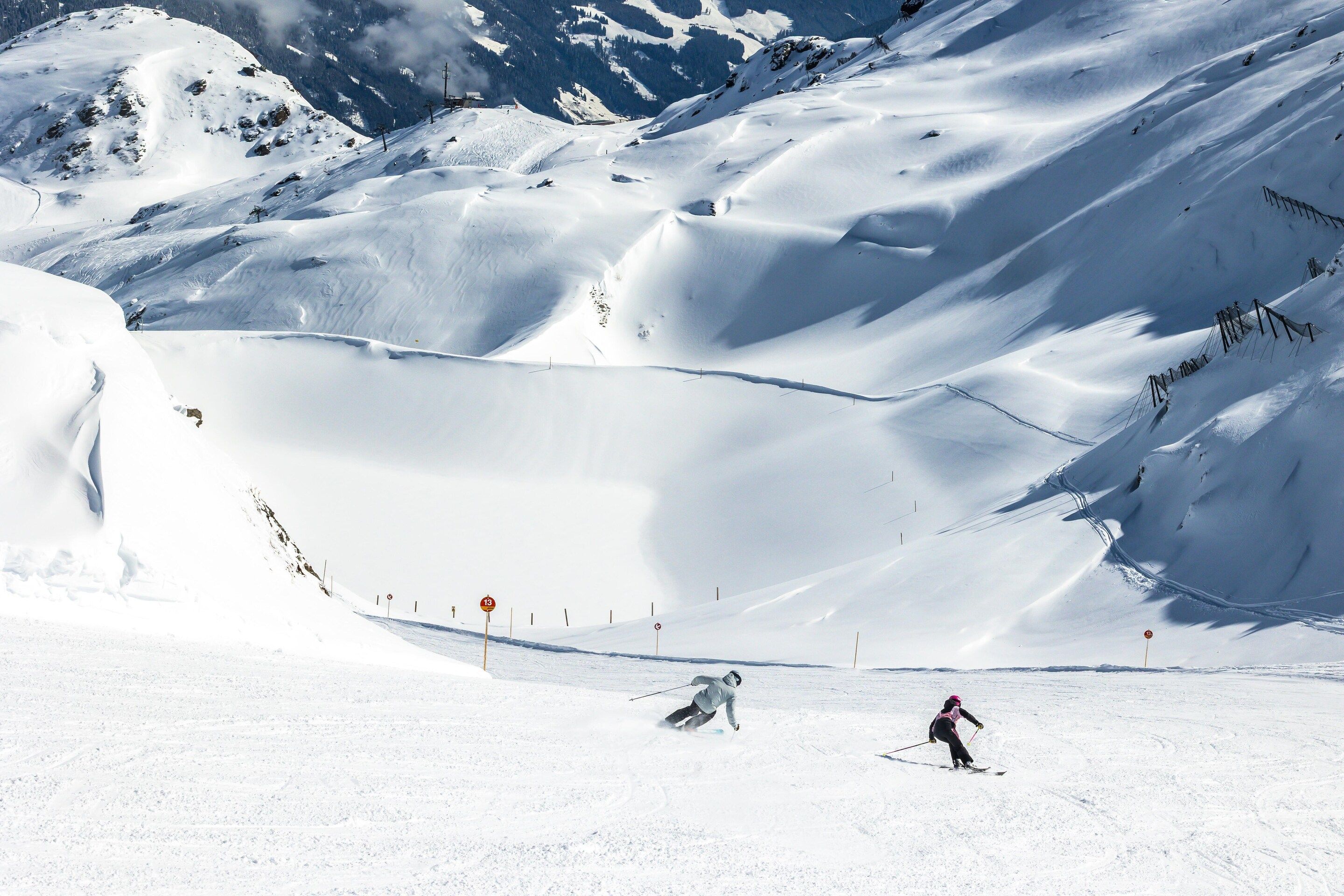 Une piste de ski enneigée, avec des pistes balisées, et une personne qui skie.