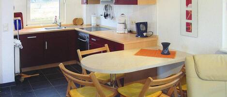 A compact kitchen with a dining table, chairs, a coffee maker, and a window.