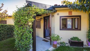 A small house with a covered entrance, a window with curtains, and a garden with potted plants. - Bungalow in Riotorto Near sea Beach (Piombino)