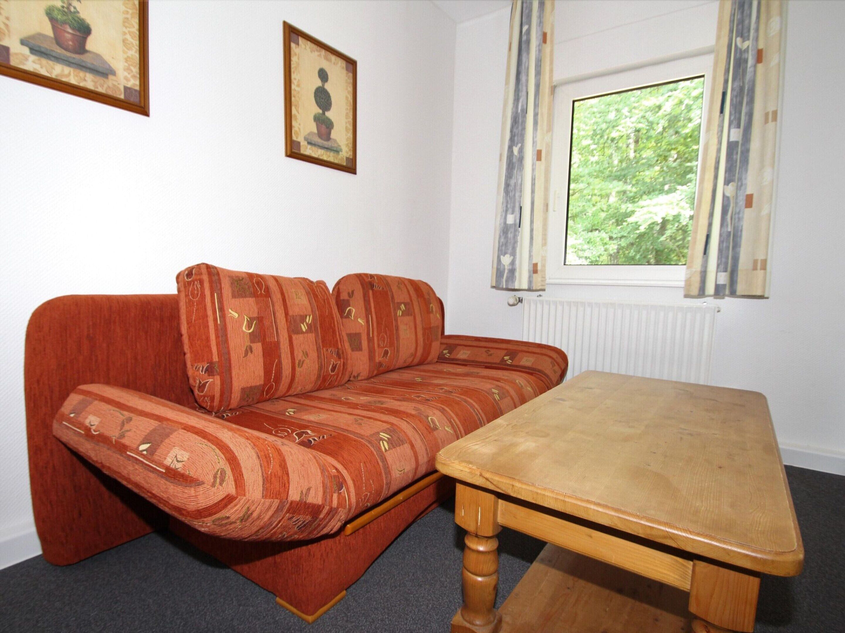 A room with a wooden table and a sofa with patterned cushions.