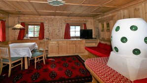 A cozy cabin-style room with a wooden ceiling, a dining table with chairs, a sofa, and a unique white chair with green circles. - Apartment and Terrace in Langenfeld (Laengenfeld)