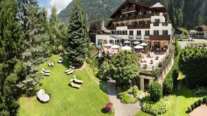 A hotel with a large outdoor seating area, multiple balconies, and a mountainous backdrop. - Apartment and Terrace in Langenfeld (Laengenfeld)