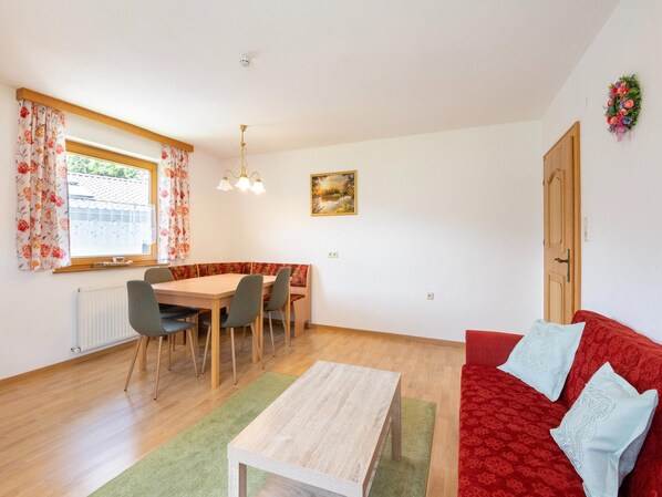 A dining area with a table and chairs, a sofa, a radiator, and a window with curtains. - Chalet in Mayrhofen Near Penken Ski Lift (Brandberg)