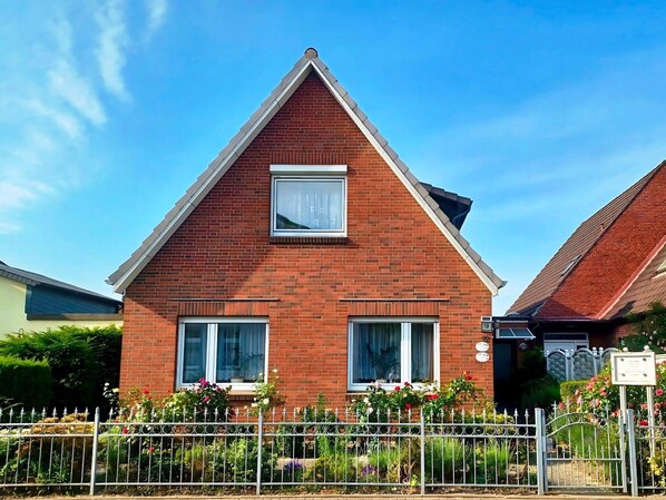 A two-story house with a red brick facade, two windows with white frames, and a small balcony with a white railing. - Ferienwohnung im Appartementhaus Stapel, Busum (Büsum)