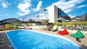 A modern hotel with a swimming pool, lounge chairs, and a glass building. - Residence Riviera Palace, Loano (Loano)