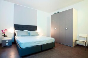 A modern bedroom with a bed, nightstands, a wardrobe, and a chair. - Residence Riviera Palace, Loano (Loano)