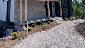 A modern two-story house with a stone facade, large windows, and a covered porch. - Le Lord, River view, trail and snowmobile (Les Éboulements)