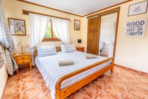 A bedroom with a wooden bed, a nightstand, a lamp, and a window with curtains. - Luxurious Private Cabin Pool Hottub & Fireplace (Alhaurin el Grande)