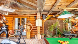 A wooden cabin interior with a pool table, exercise equipment, and various decorations. - Luxurious Private Cabin Pool Hottub & Fireplace (Alhaurin el Grande)