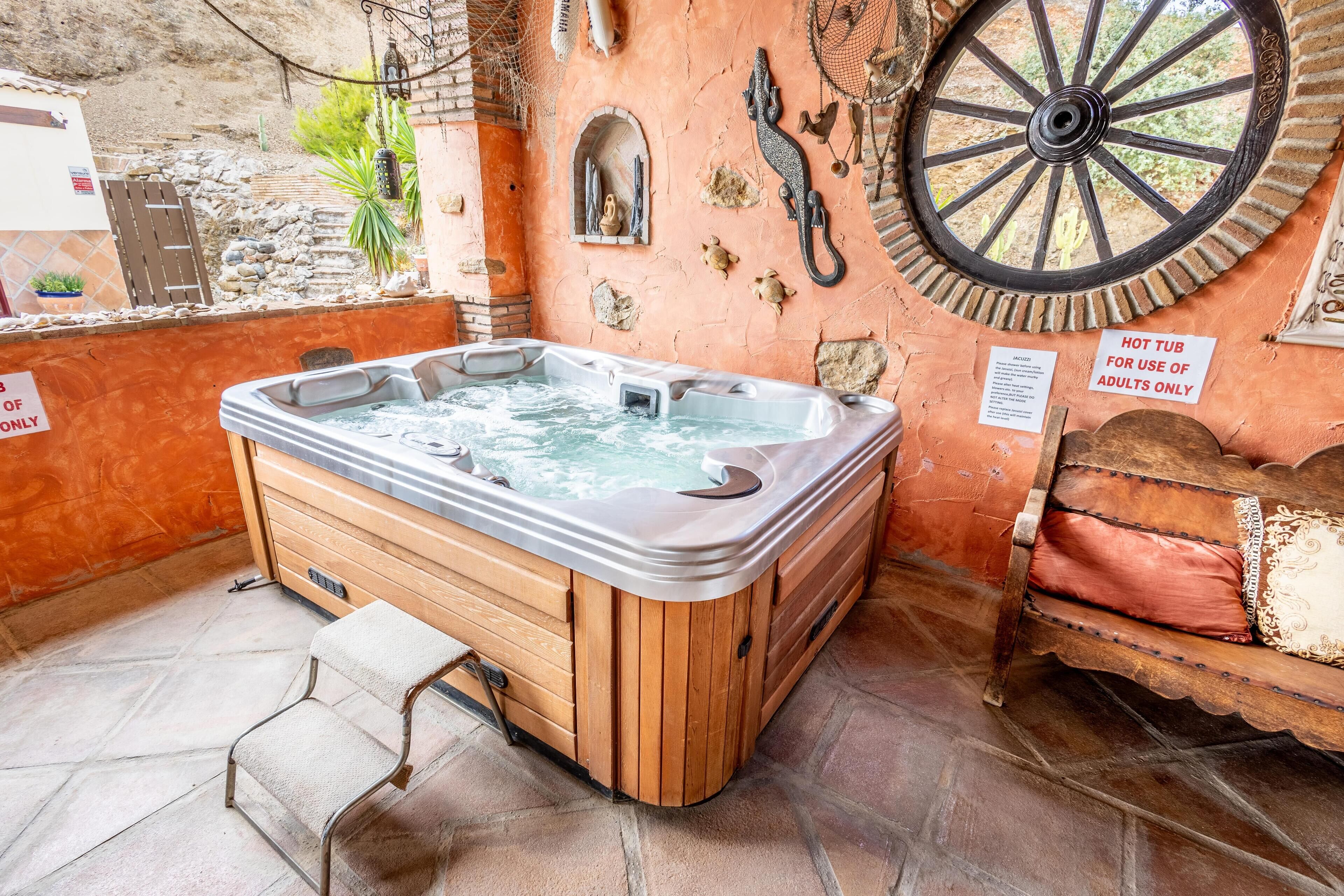 Ein Whirlpool in ländlicher Umgebung mit Steinwänden, einer Holzbank und einem großen Wasserrad.