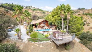 A wooden cabin with a pool, surrounded by palm trees and cacti, set on a hillside. - Luxurious Private Cabin Pool Hottub & Fireplace (Alhaurin el Grande)