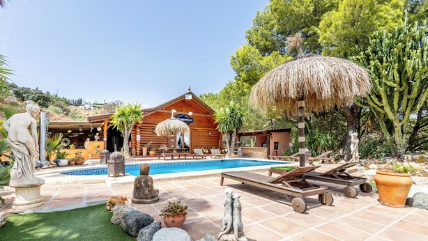 A pool area with lounge chairs, a thatched umbrella, and a wooden cabin. - Luxurious Private Cabin Pool Hottub & Fireplace (Alhaurin el Grande)