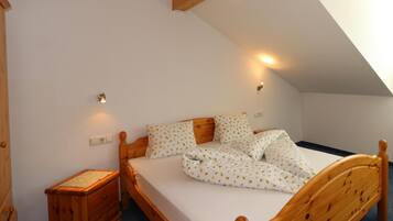 A bedroom with a wooden bed, white bedding, and a sloped ceiling.