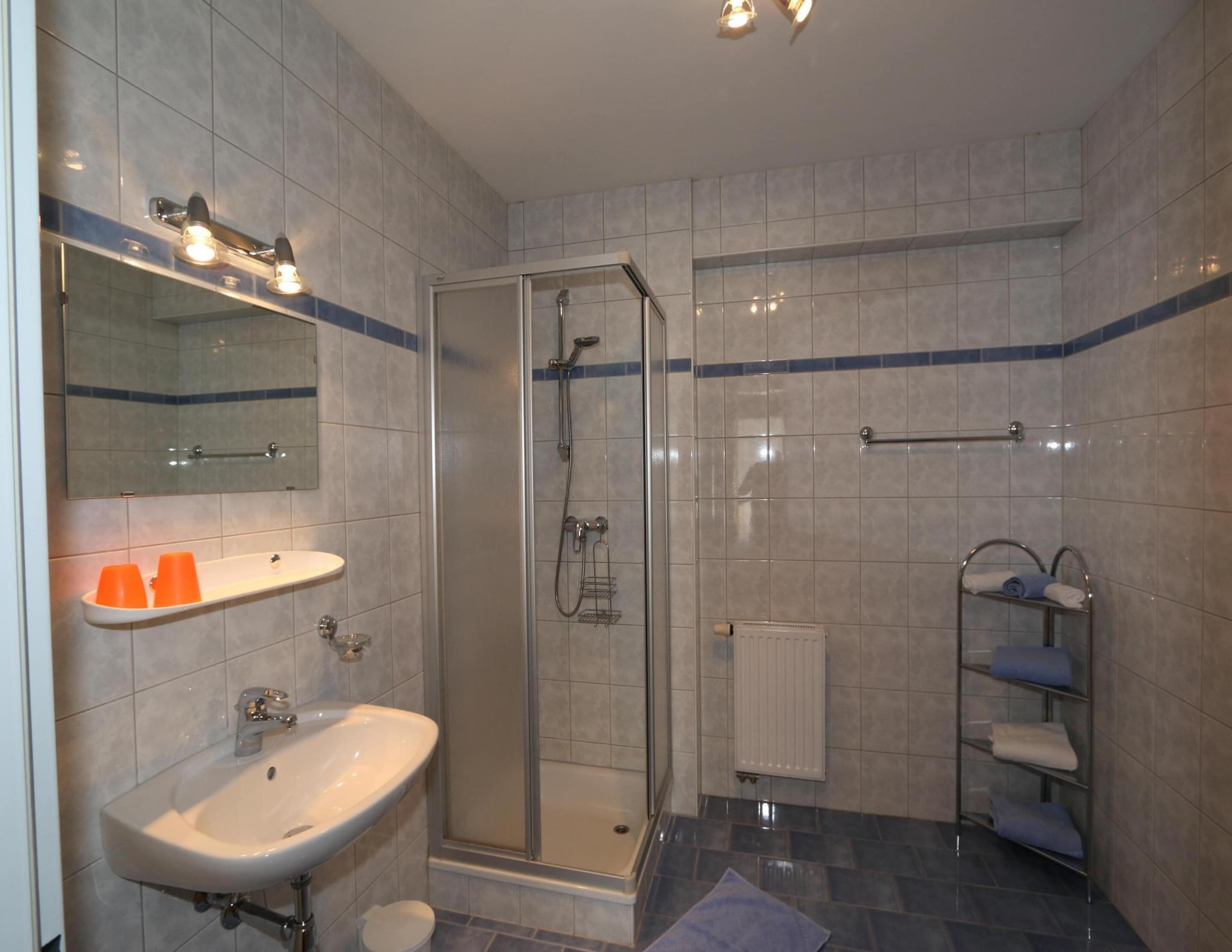 A modern bathroom with a glass-enclosed shower, a sink with a mirror, and a towel rack.