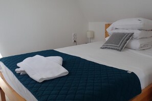 A neatly made bed with a teal quilted bedspread, white pillows, and a folded white towel on the left side. - Holiday Home, Kolczewo (gmina Wolin)