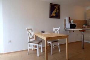 A small, clean kitchen with a wooden table and white chairs, a microwave, and a painting on the wall. - Holiday Home, Kolczewo (gmina Wolin)