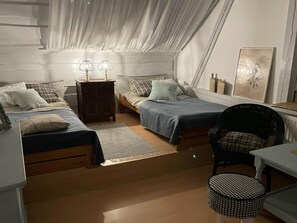 Un dormitorio acogedor y compacto con dos camas individuales, una mesita, una silla y una mesita de noche.
